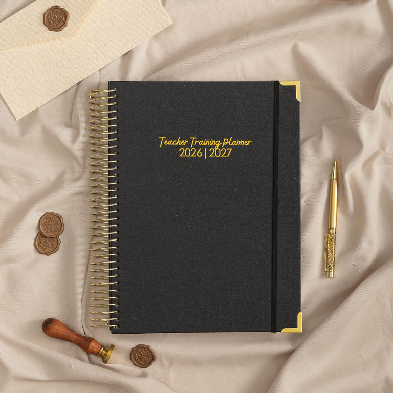 Black planner with gold text on a beige fabric background