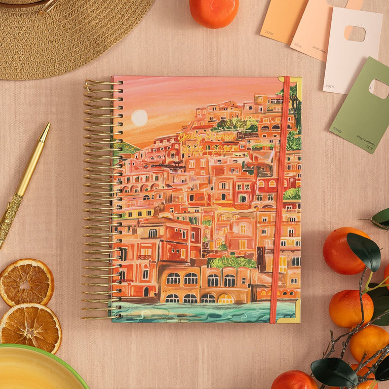 Colorful notebook with a scenic cover on a wooden surface with decorative items.