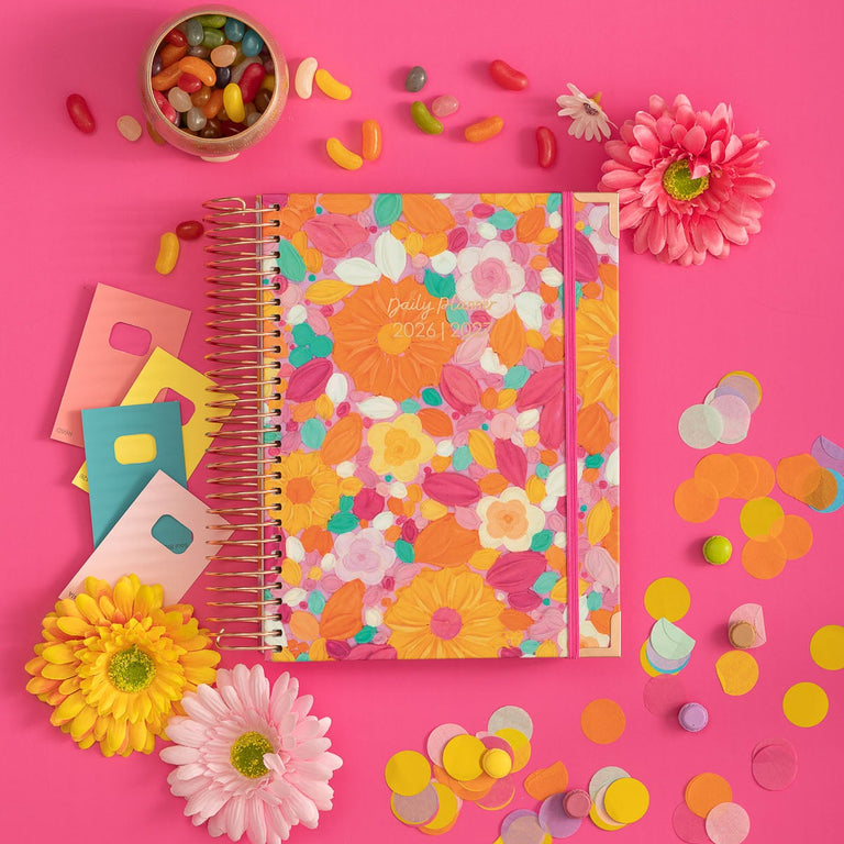 Colorful notebook with floral design on a pink background with flowers and candies.