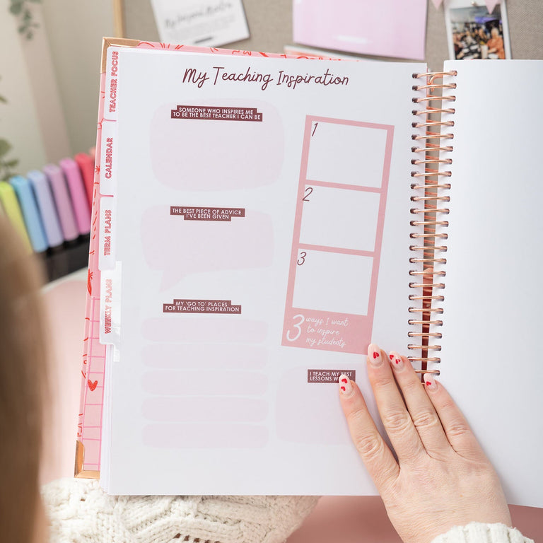 Person holding a spiral-bound notebook with a pink interior page titled 'My Teaching Inspiration'.