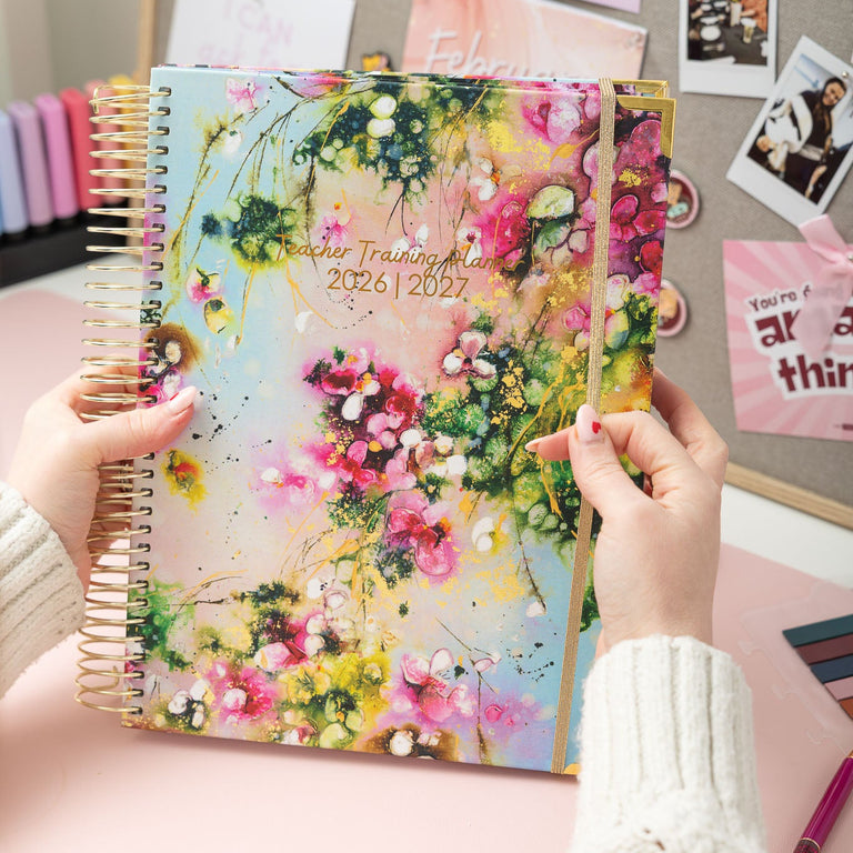 Floral planner held by hands with a decorative background