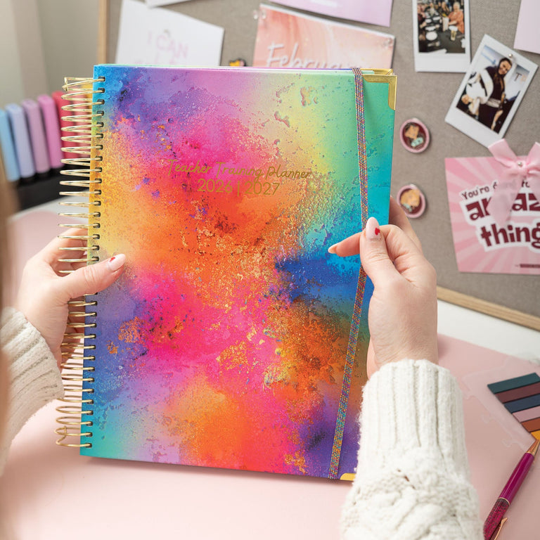 Colorful planner held by hands with a desk background