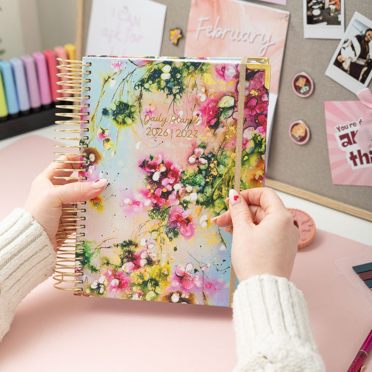 Person holding a floral planner with a decorative background