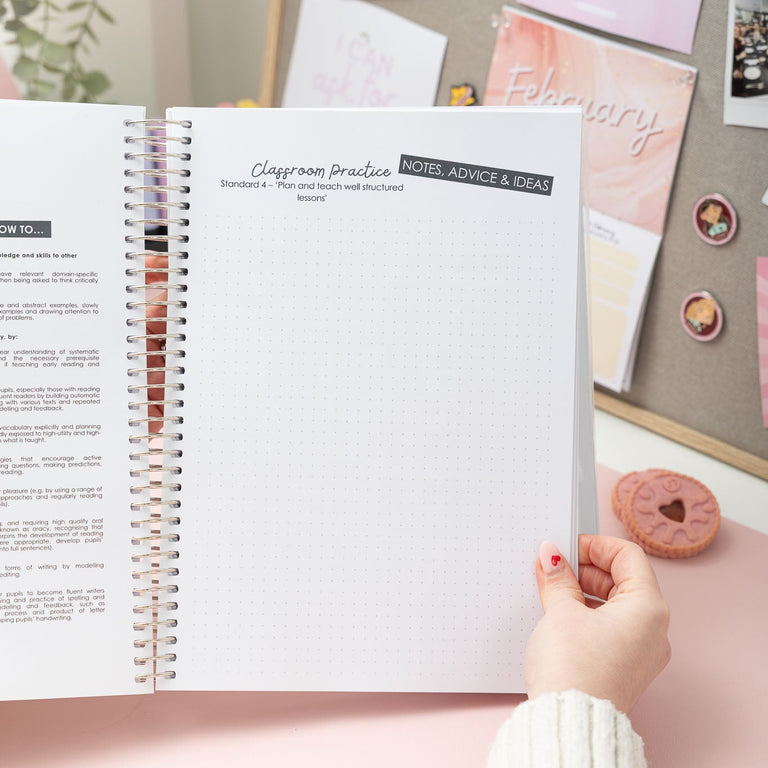 Person holding an open spiral-bound book on a desk with decorative items in the background