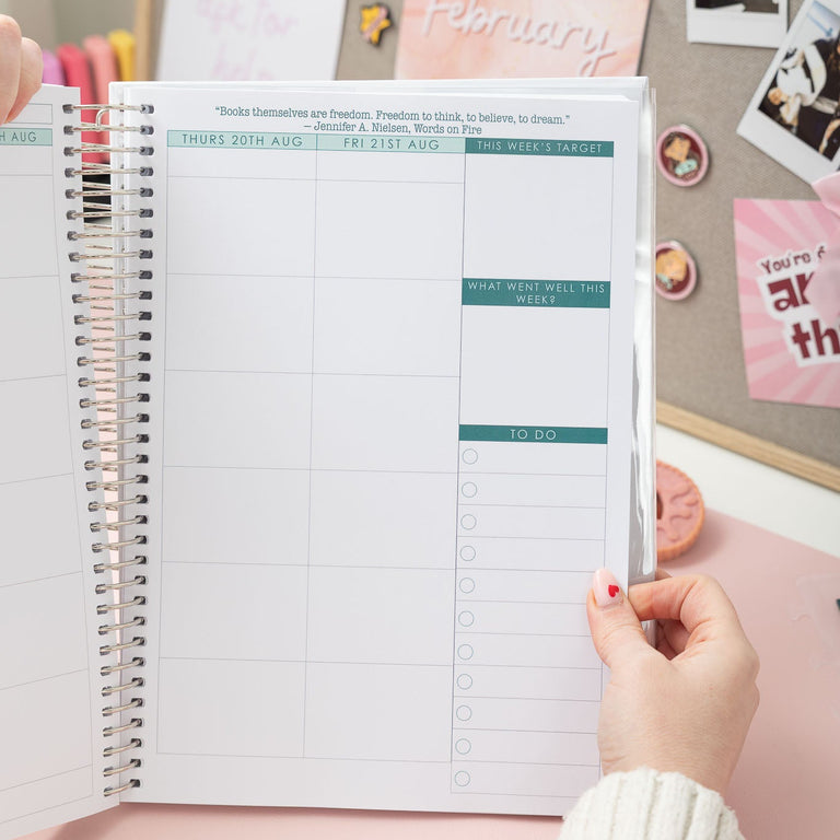 Person holding a planner with a decorative background featuring photos and notes.