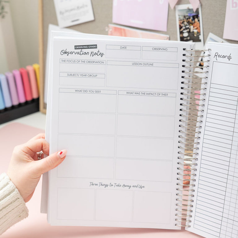 Person holding a spiral-bound notebook with visible pages on a pink surface.