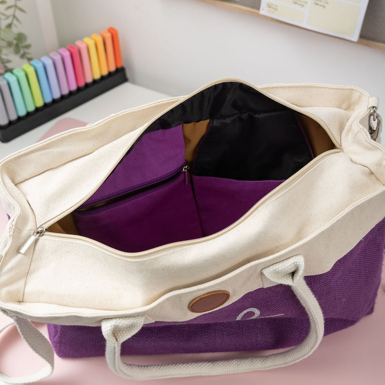 Purple and beige bag on a desk with colorful markers in the background