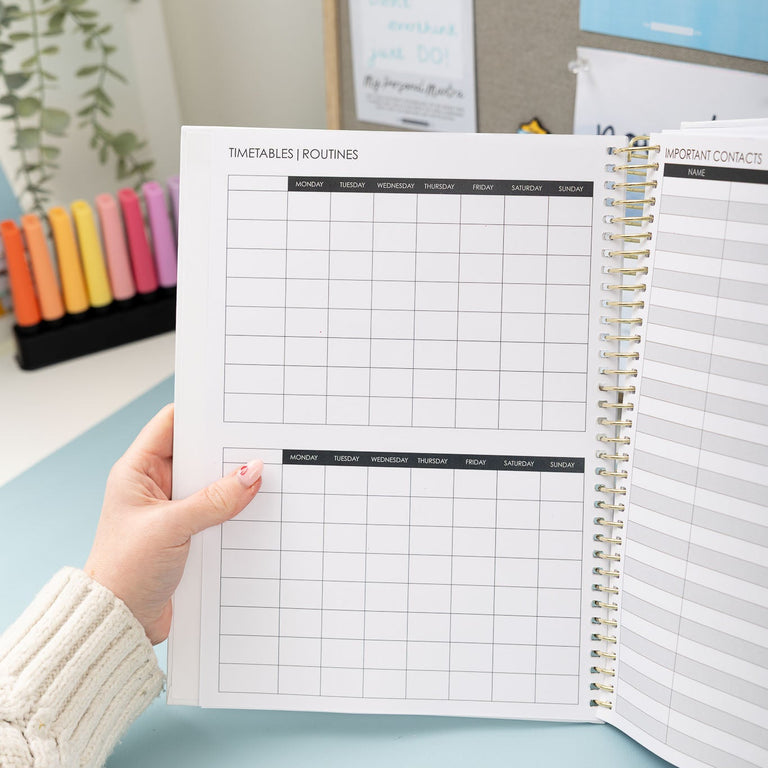 Person holding a planner with a grid layout on a light blue surface.