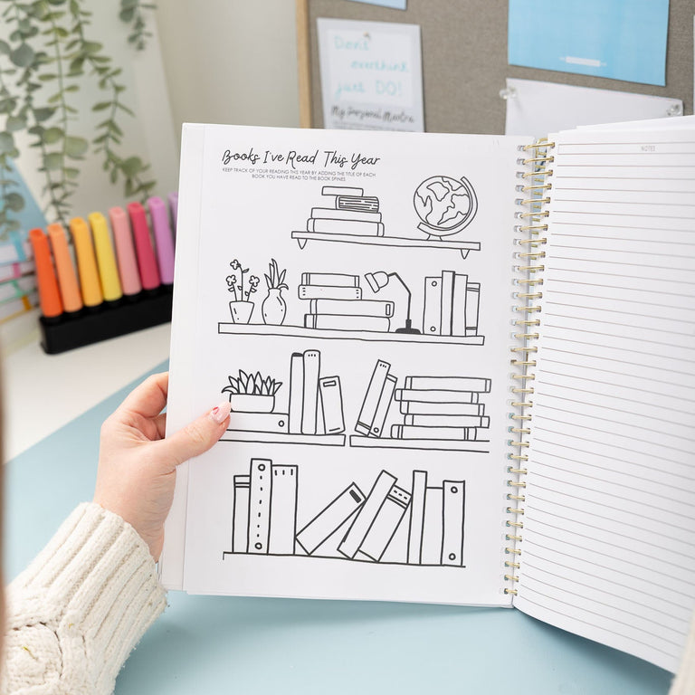 Person holding a notebook with a bookshelf illustration on a light blue surface.