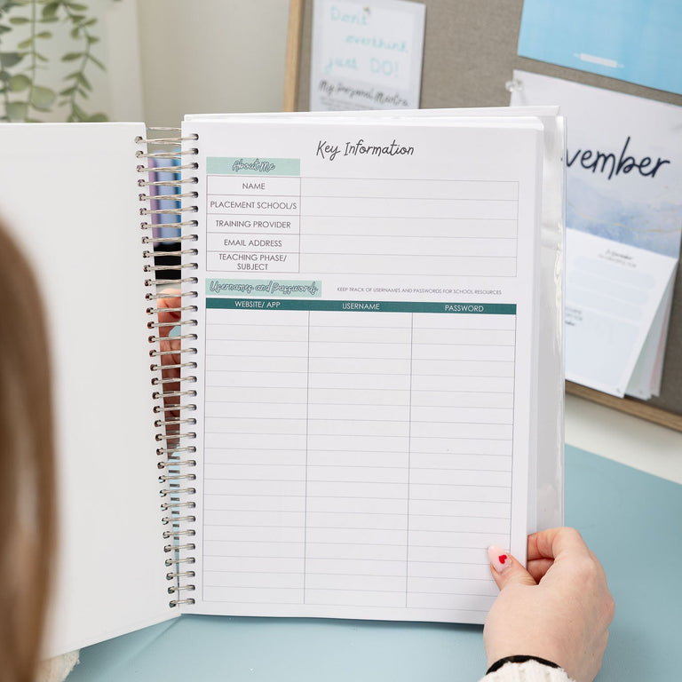 Person holding a planner with a calendar on a desk, surrounded by motivational posters.