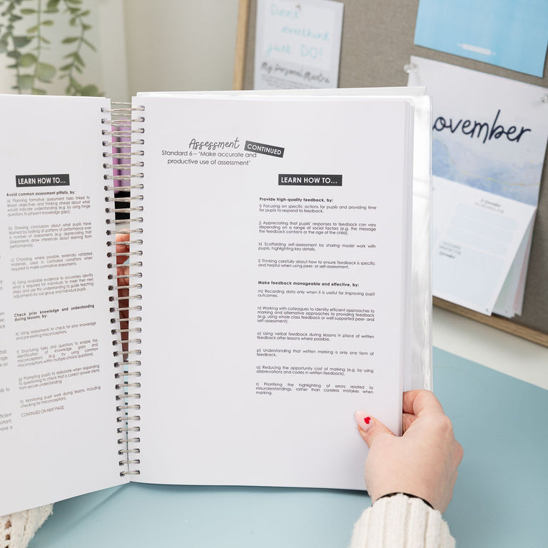 Person holding an open planner with a bulletin board in the background