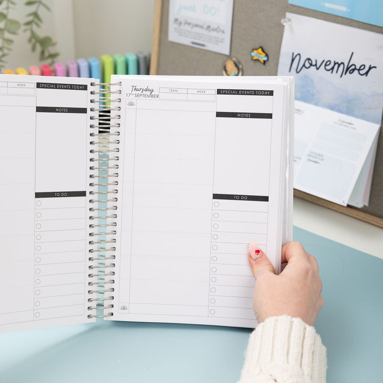 Person holding a planner with a calendar in the background