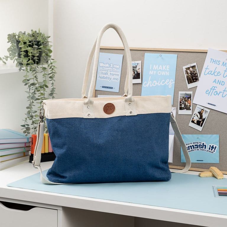 Blue and beige bag on a desk with a whiteboard in the background