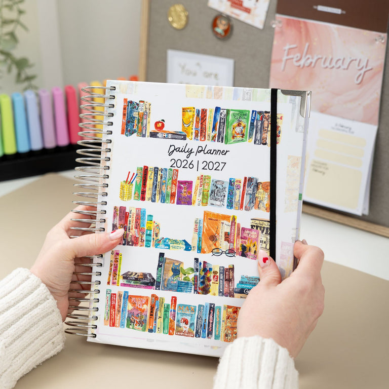 Person holding a colorful daily planner with a home office background