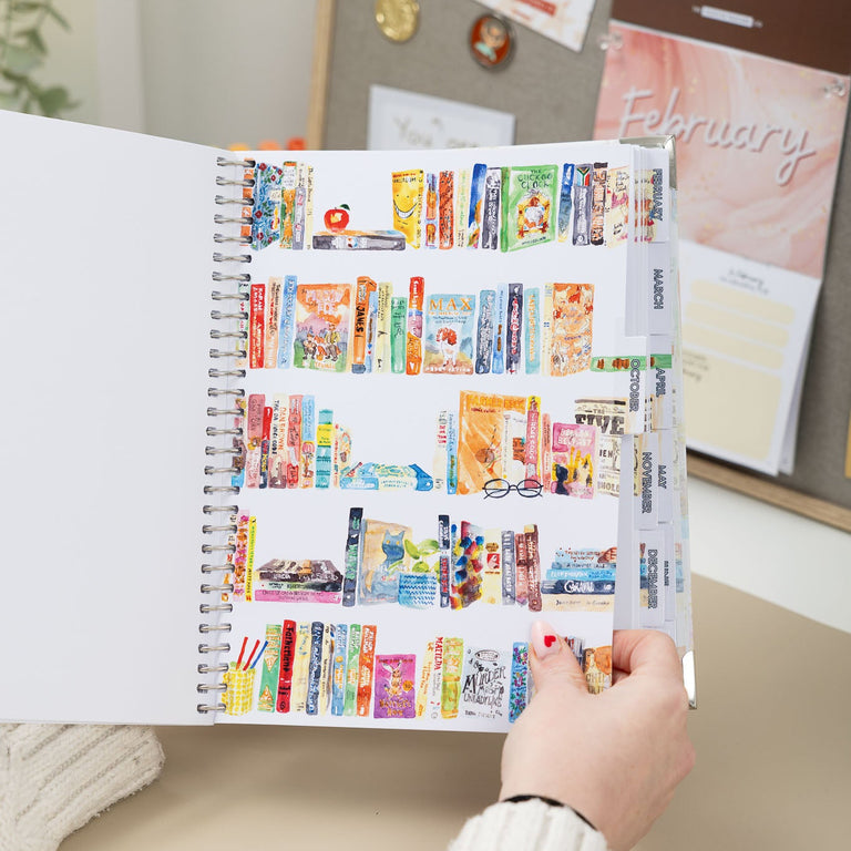 Person holding a planner with colorful monthly tabs in an office setting
