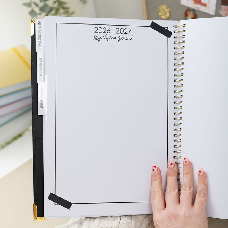 Open planner with 2026-2027 dates, held by a person wearing a white sweater.