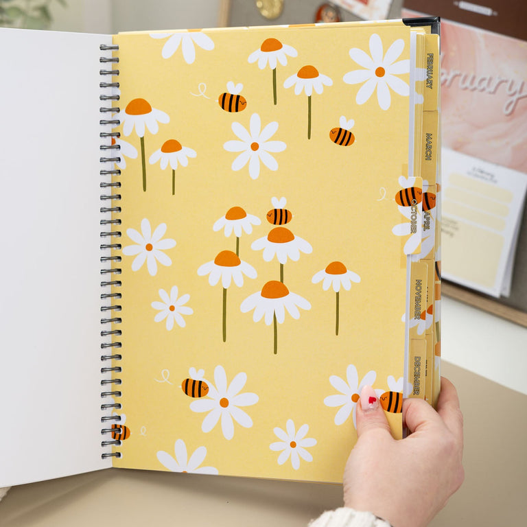 Yellow notebook with floral pattern held by a person indoors