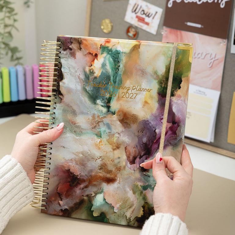 Person holding a planner with a colorful cover in an office setting