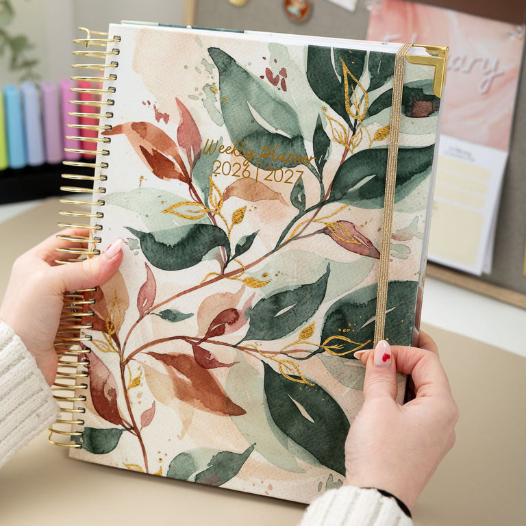 Person holding a floral planner with a desk and decor in the background