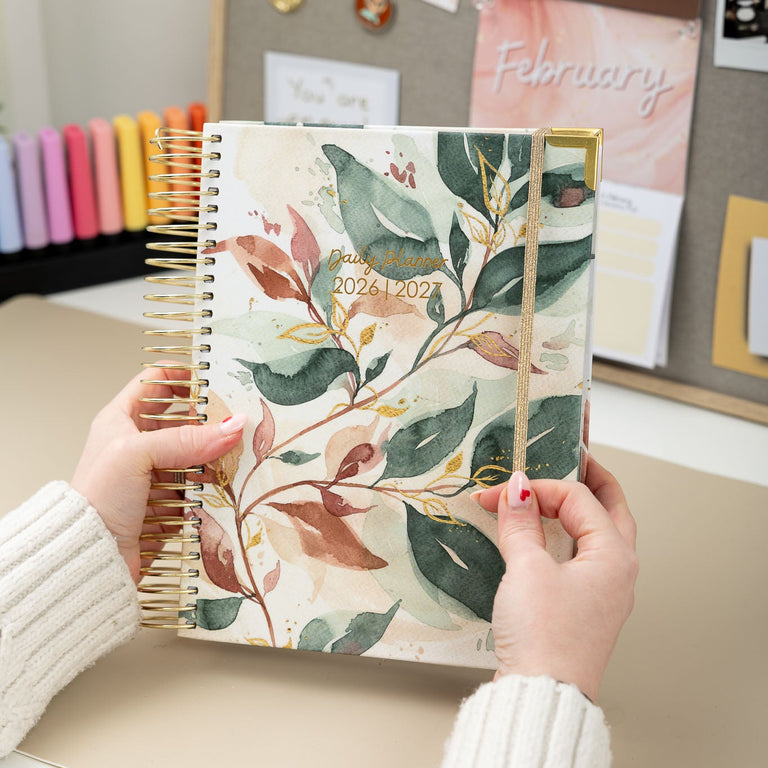 Person holding a floral planner with a desk and wall decorations in the background