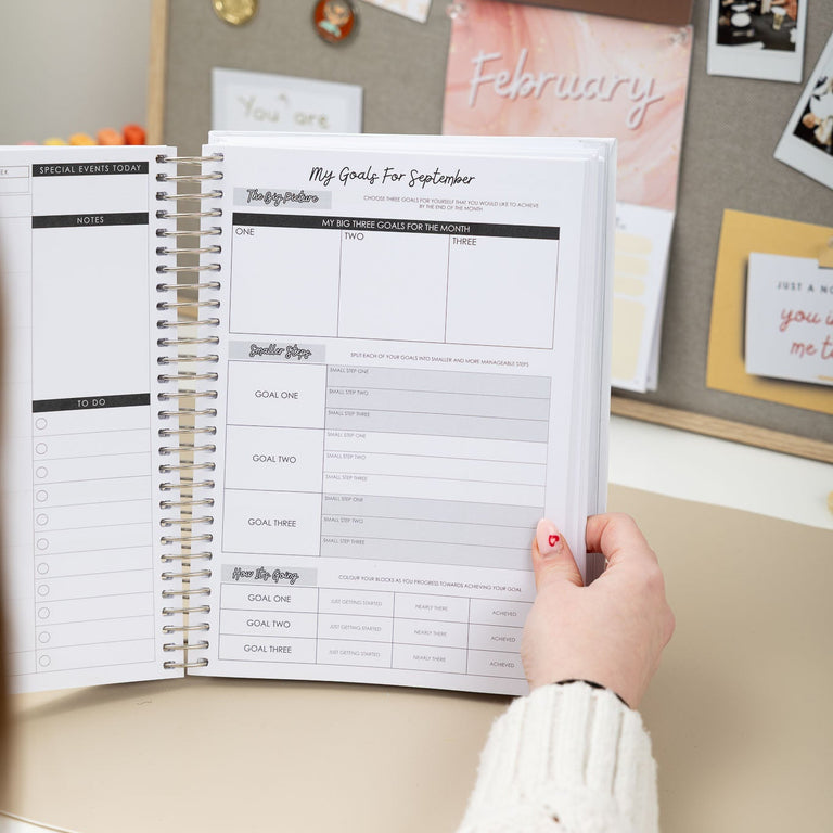 Person holding a planner with a decorative wall in the background