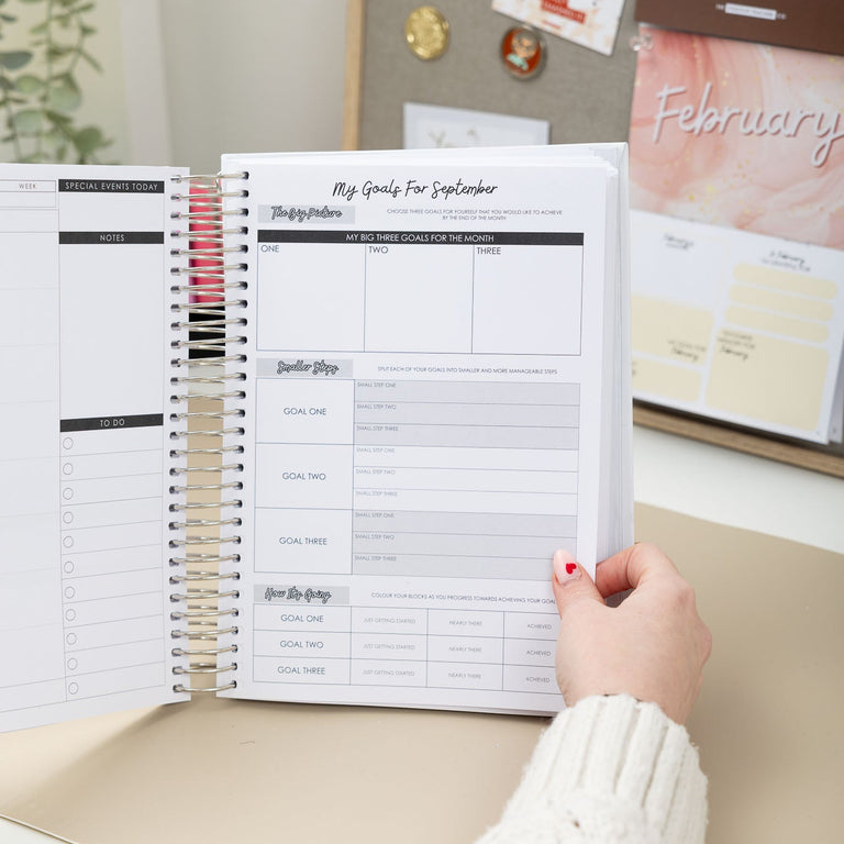 Person holding a planner with a calendar in the background