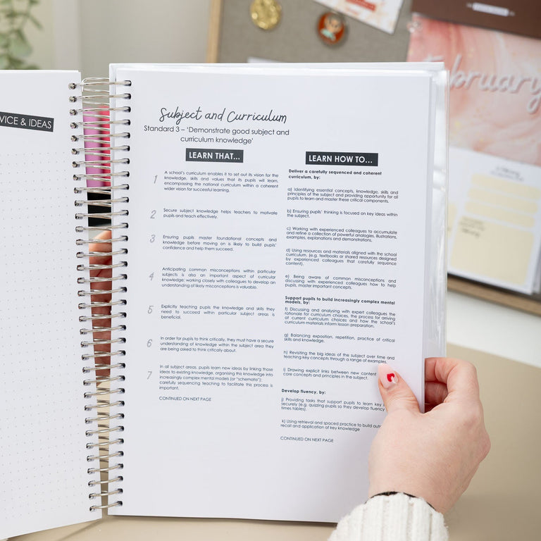 Person holding an open spiral-bound notebook with text on a desk.