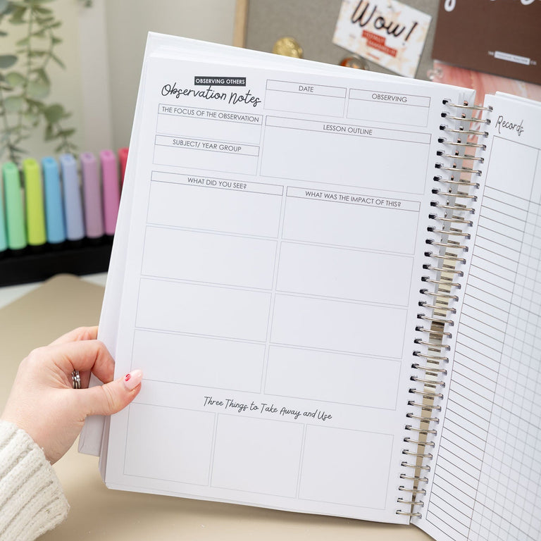 Person holding a spiral-bound planner with a visible table and decor in the background