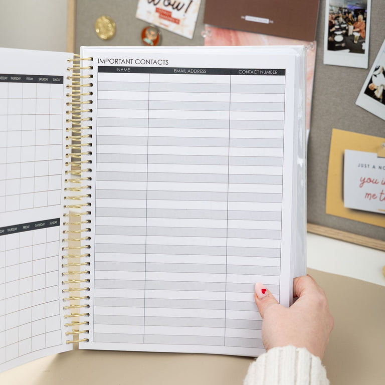 Person holding an open planner with a motivational quote on a corkboard background