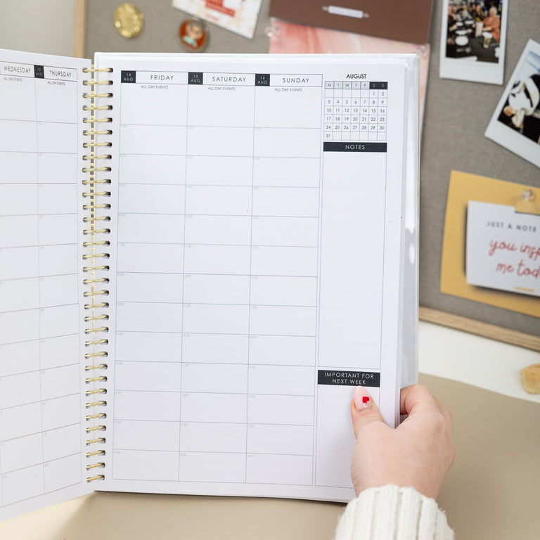 Person holding a planner with motivational posters on the wall behind