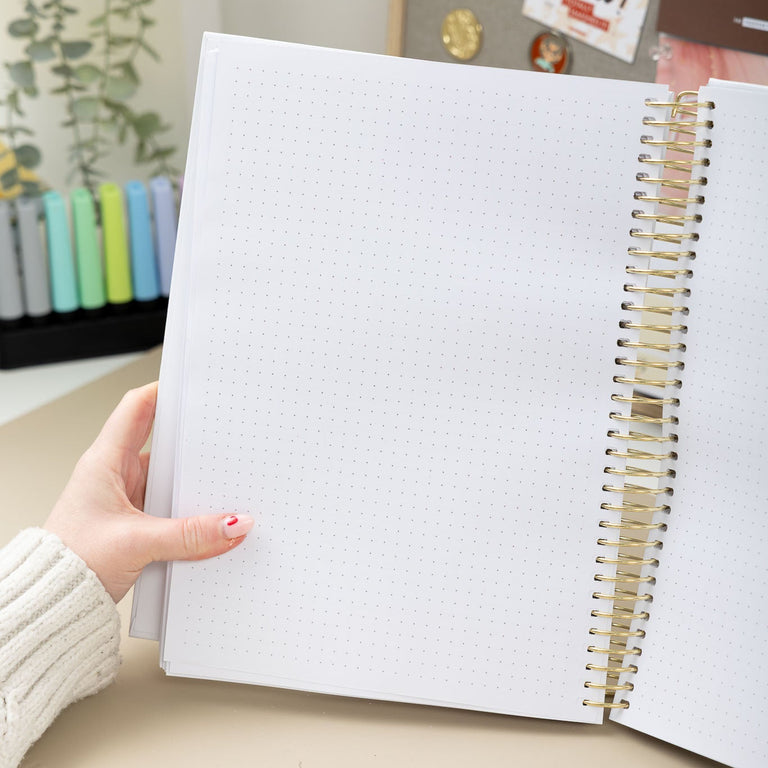 Person holding a spiral-bound notebook with a decorative background