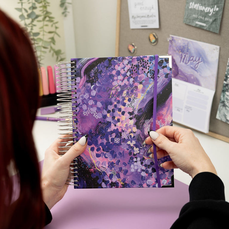 Person holding a purple notebook with abstract design in an office setting