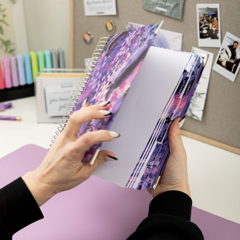 Person holding a colorful notebook with a desk and photos in the background