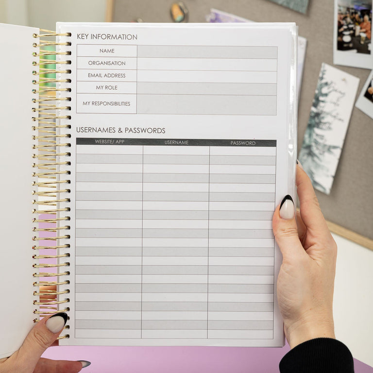 Person holding a spiral-bound notebook with key information and usernames/passwords pages.