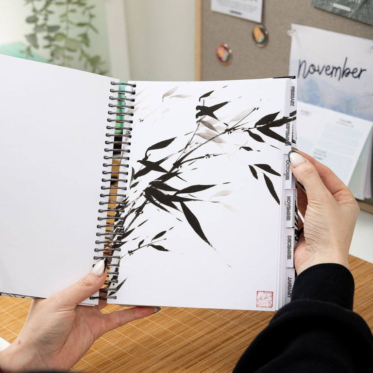 Person holding a planner with bamboo design on a desk