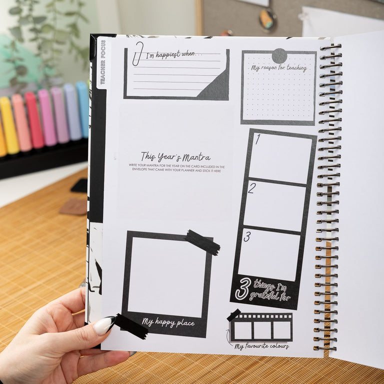 Person holding a planner with design elements on a desk.