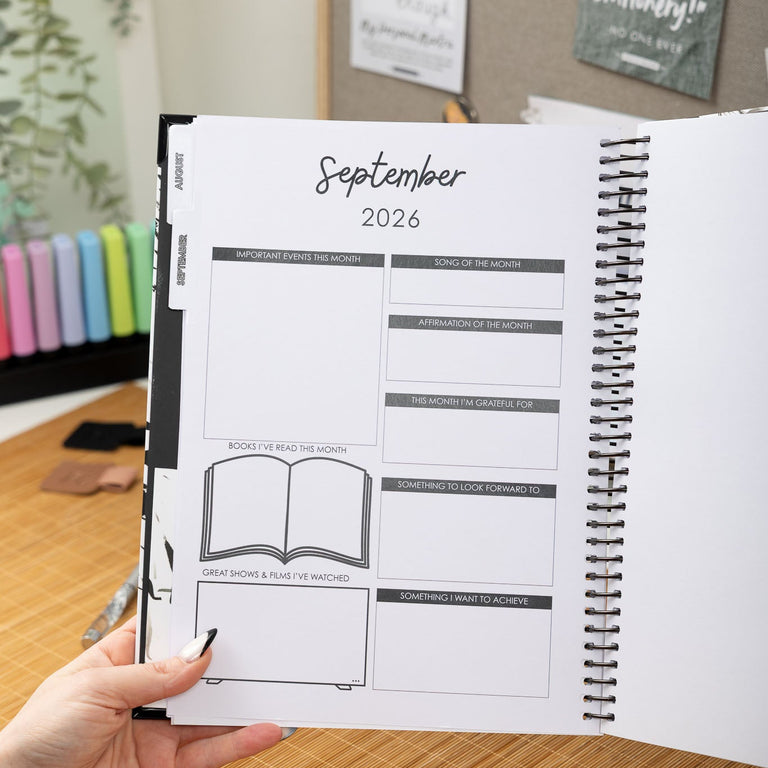 Person holding a planner with September 2026 layout on a desk.