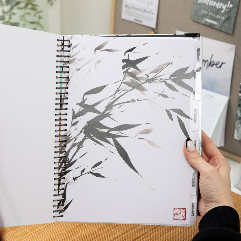 Person holding a notebook with bamboo design on a desk