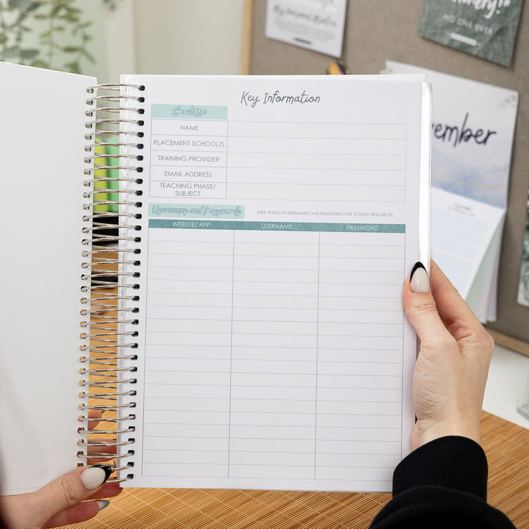 Person holding a spiral-bound planner with a grid layout on a wooden surface.
