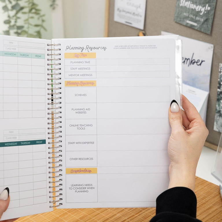 Person holding a planner with a calendar view on a desk.