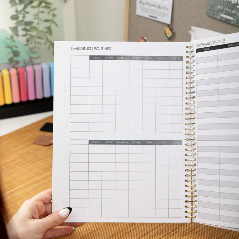 Person holding a planner open on a desk with a blurred background