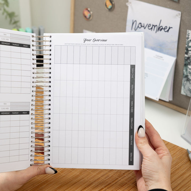Person holding a planner with grid pages against a desk background