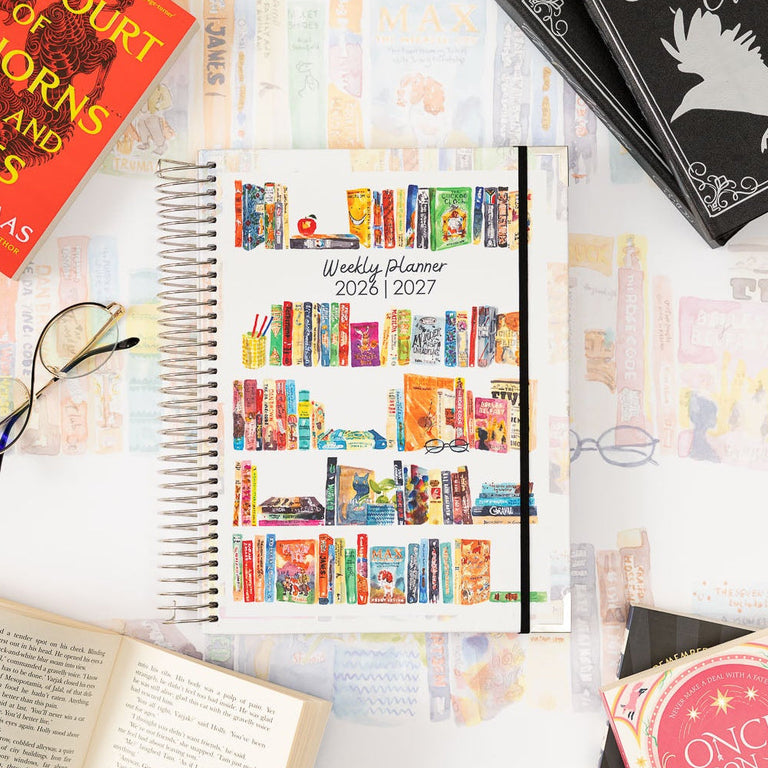 Collection of books and planners on a white surface with decorative elements.