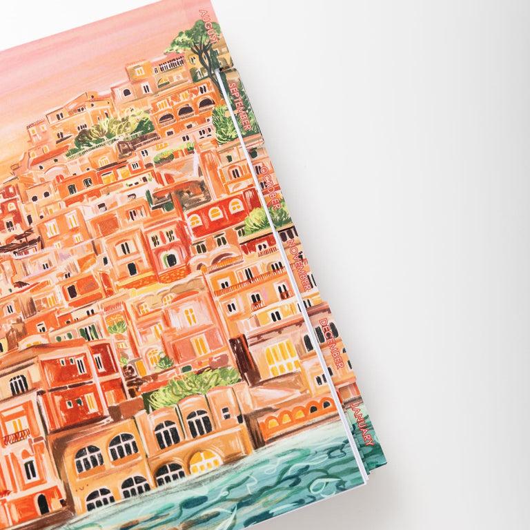Notebook with a colorful illustration of a coastal town on a white background