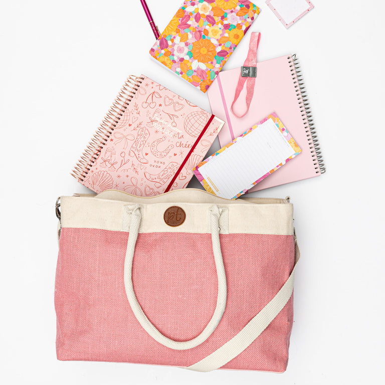 Pink tote bag with stationery items on a white background