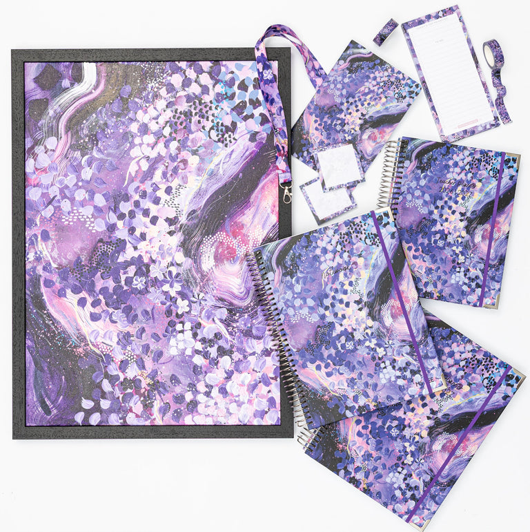 Purple and pink stationery items on a white surface