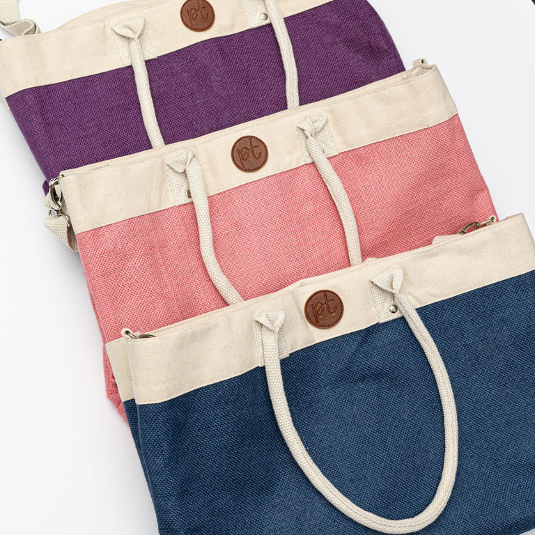 Set of three colorful tote bags with button closures on a white surface.