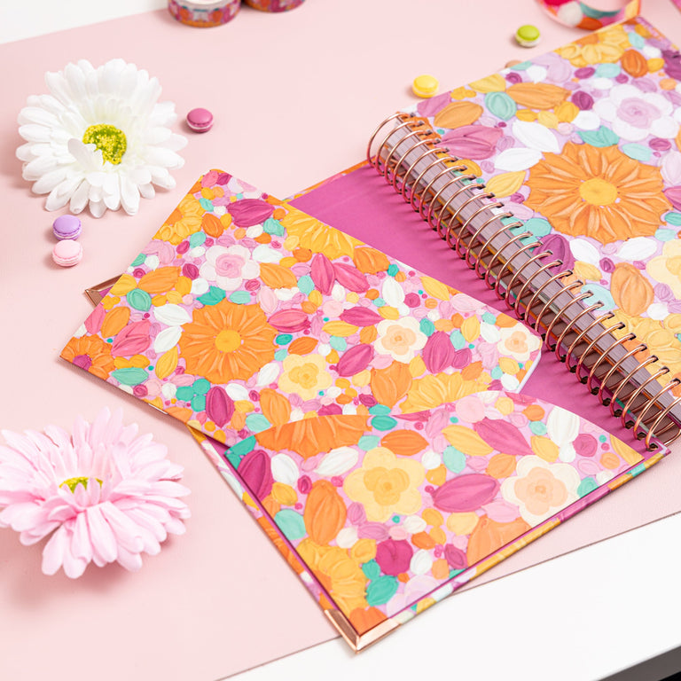 Floral notebook on a pink surface with decorative items