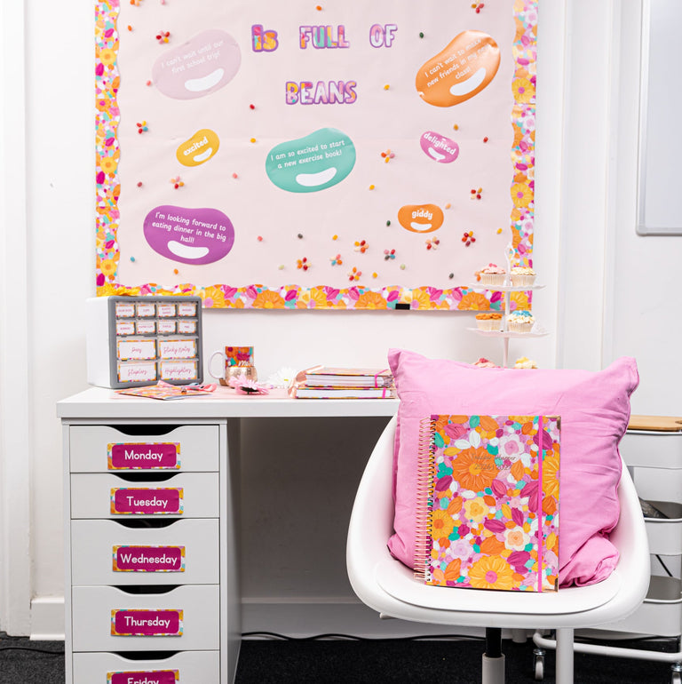Colorful classroom setup with a desk, chair, and decorative bulletin board.