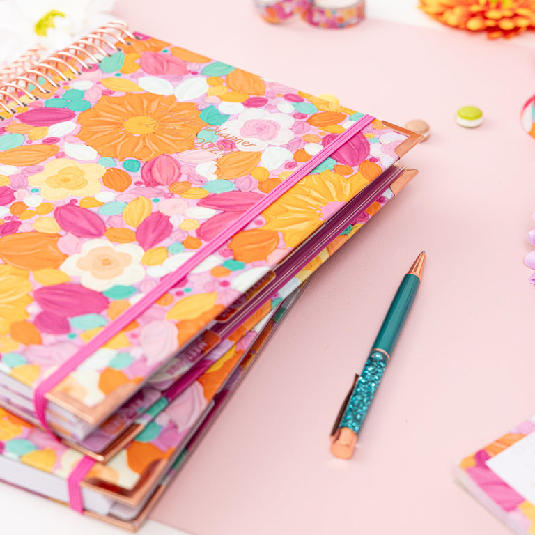 Floral notebook with a pen on a pink surface